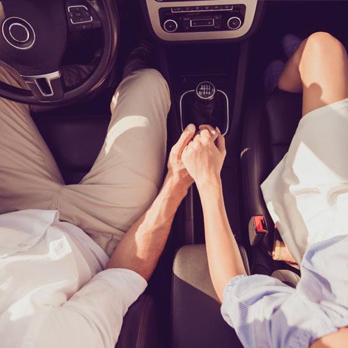 happy couple holding hands driving car